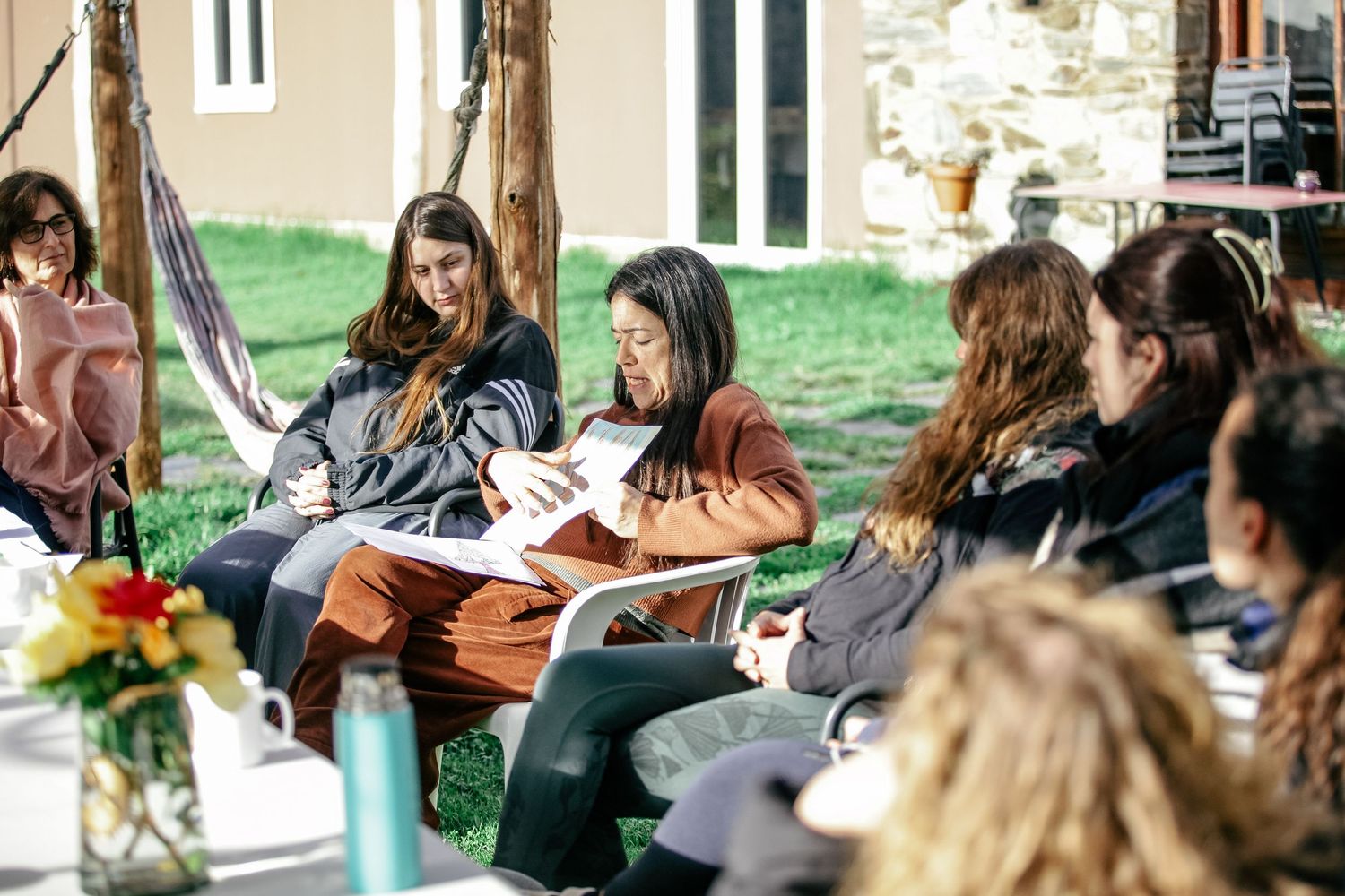 People sitting outdoors in a casual gathering on a sunny day.