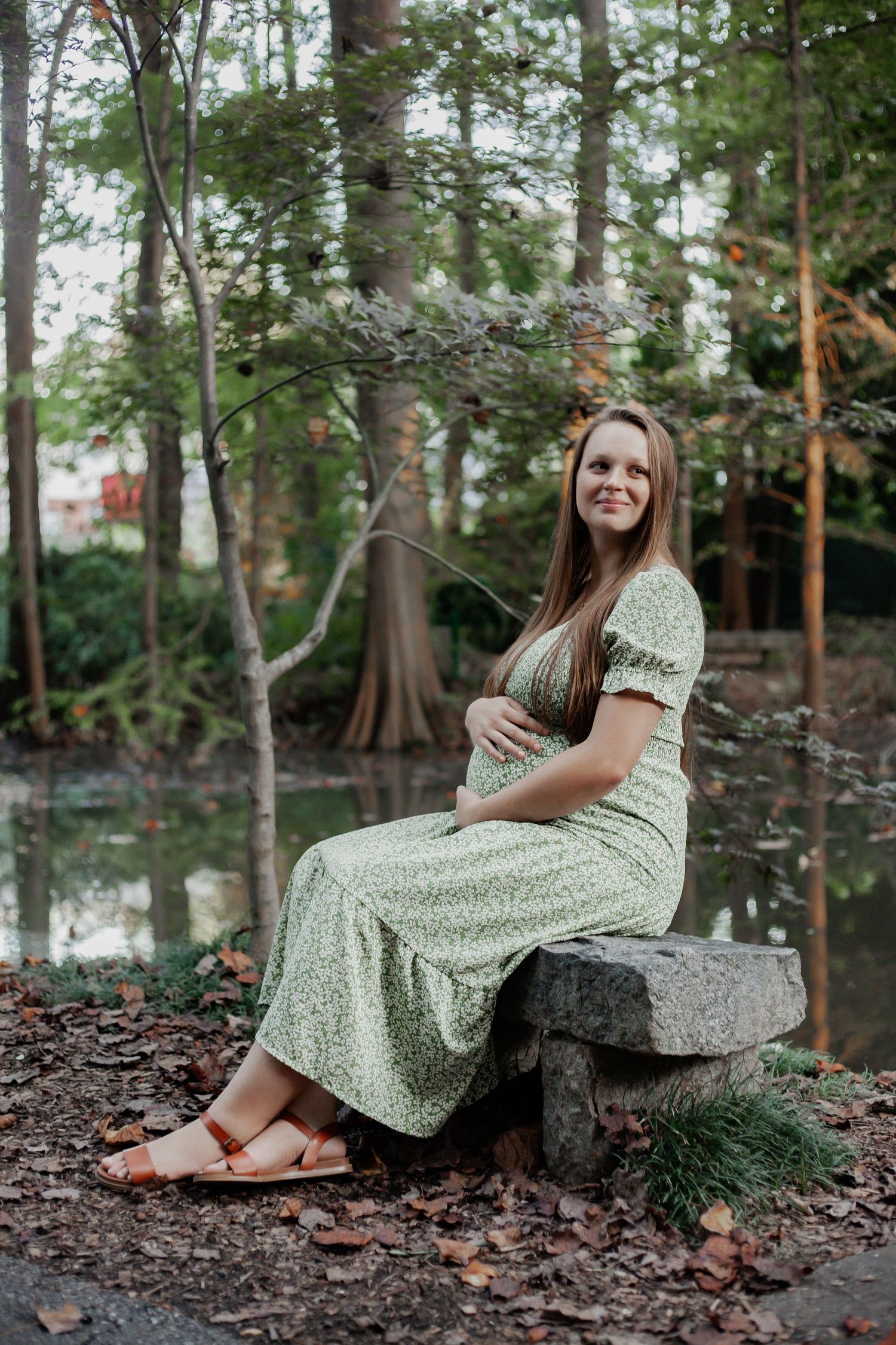 young expectant mother maternity photo in a wooded park with lake behind her in south carolina