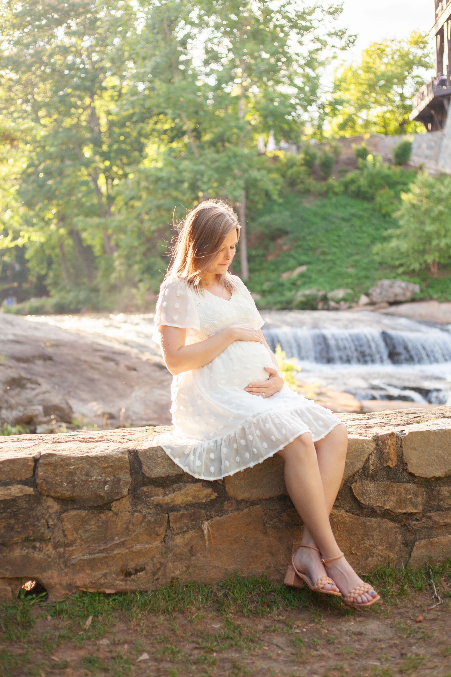 Pregnant Greenville mother holding her baby bump for a maternity photo shoot at falls park in downtown greenville.