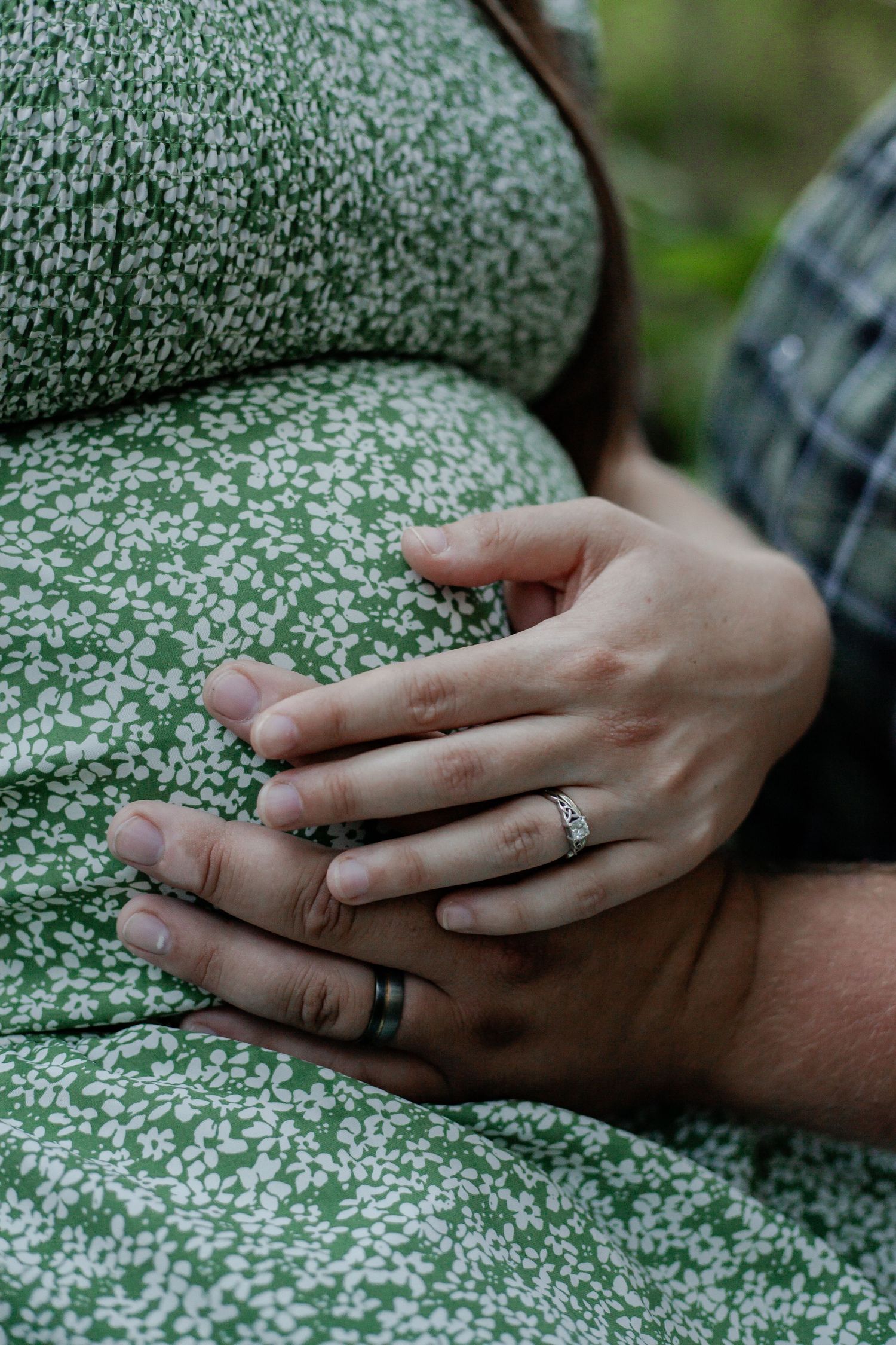 maternity photo baby bump with wedding band hands of young married couple