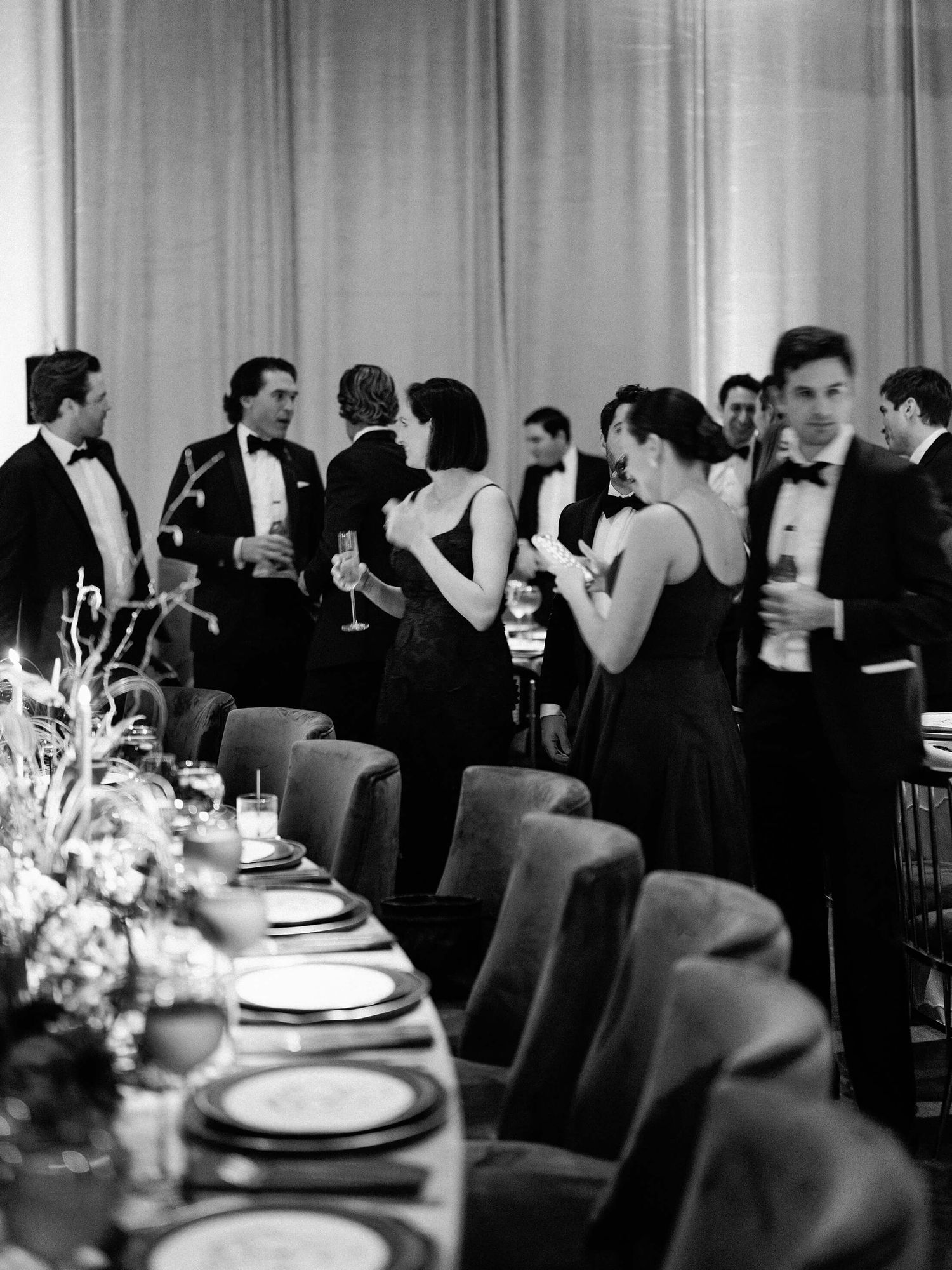 Black and white photo of an elegant dinner reception with tables set for a formal gathering.