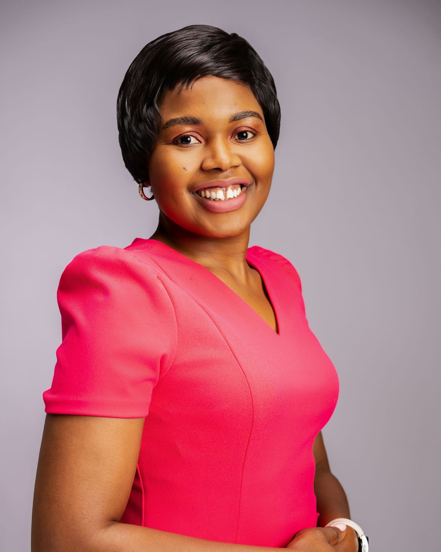 Confident Black woman smiling in a pink dress, professional headshot.