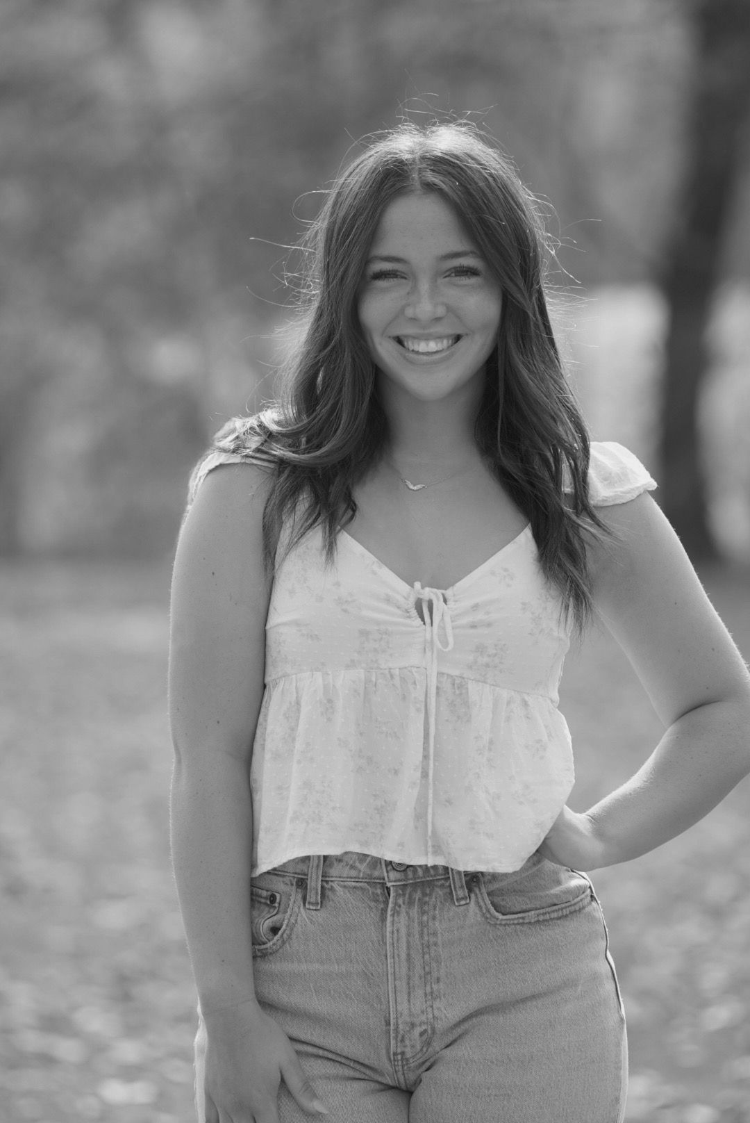 A series of black and white portrait photographs showing someone in a light-colored top and jeans outdoors.