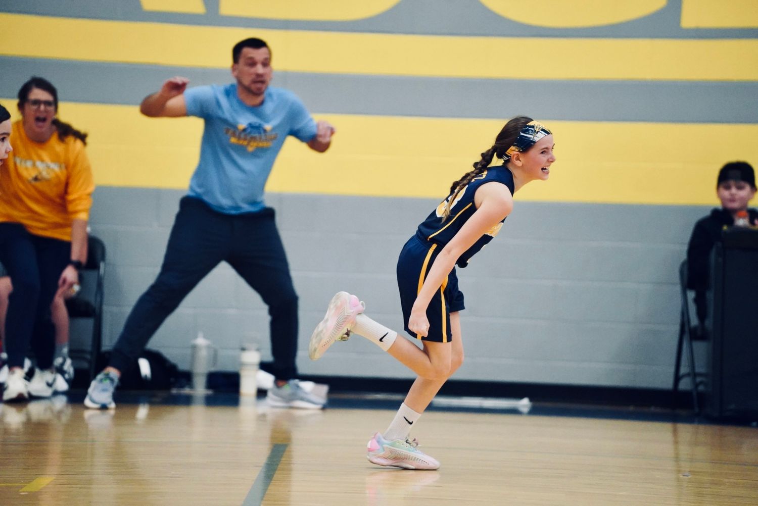 A group of athletes practicing volleyball skills in a gymnasium with blue and yellow walls.
