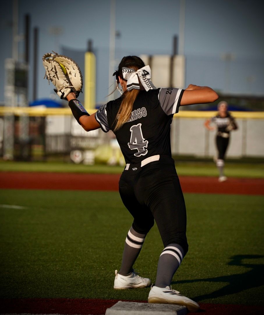 A softball player performs a sliding technique on the field during practice or gameplay.