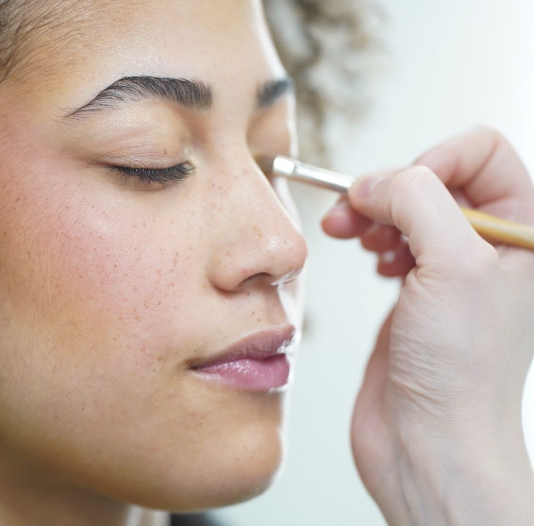 Close up profile view showing application of cosmetic product with cotton swab on facial skin.