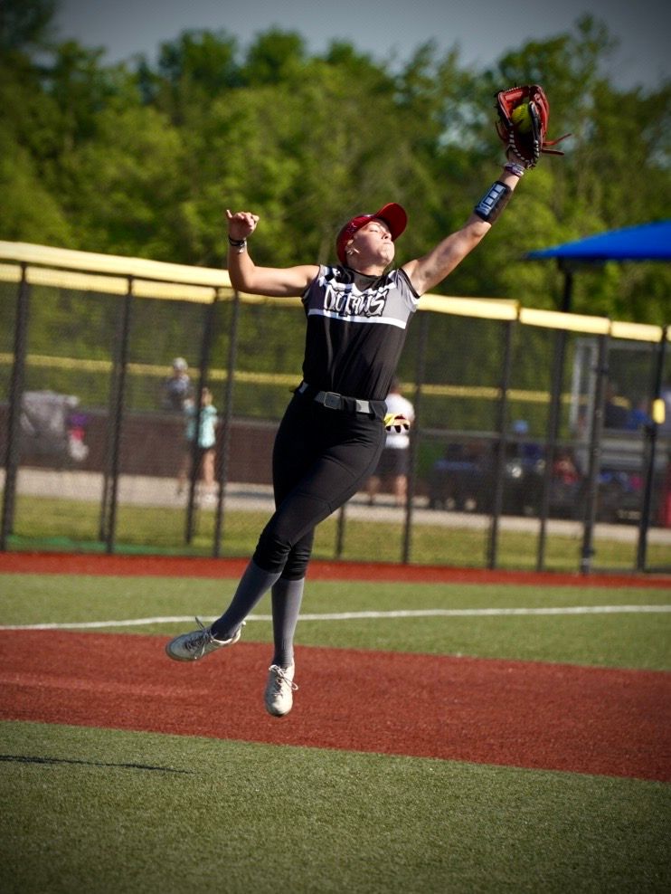 A baseball player makes an acrobatic diving catch while leaping through the air on the field.
