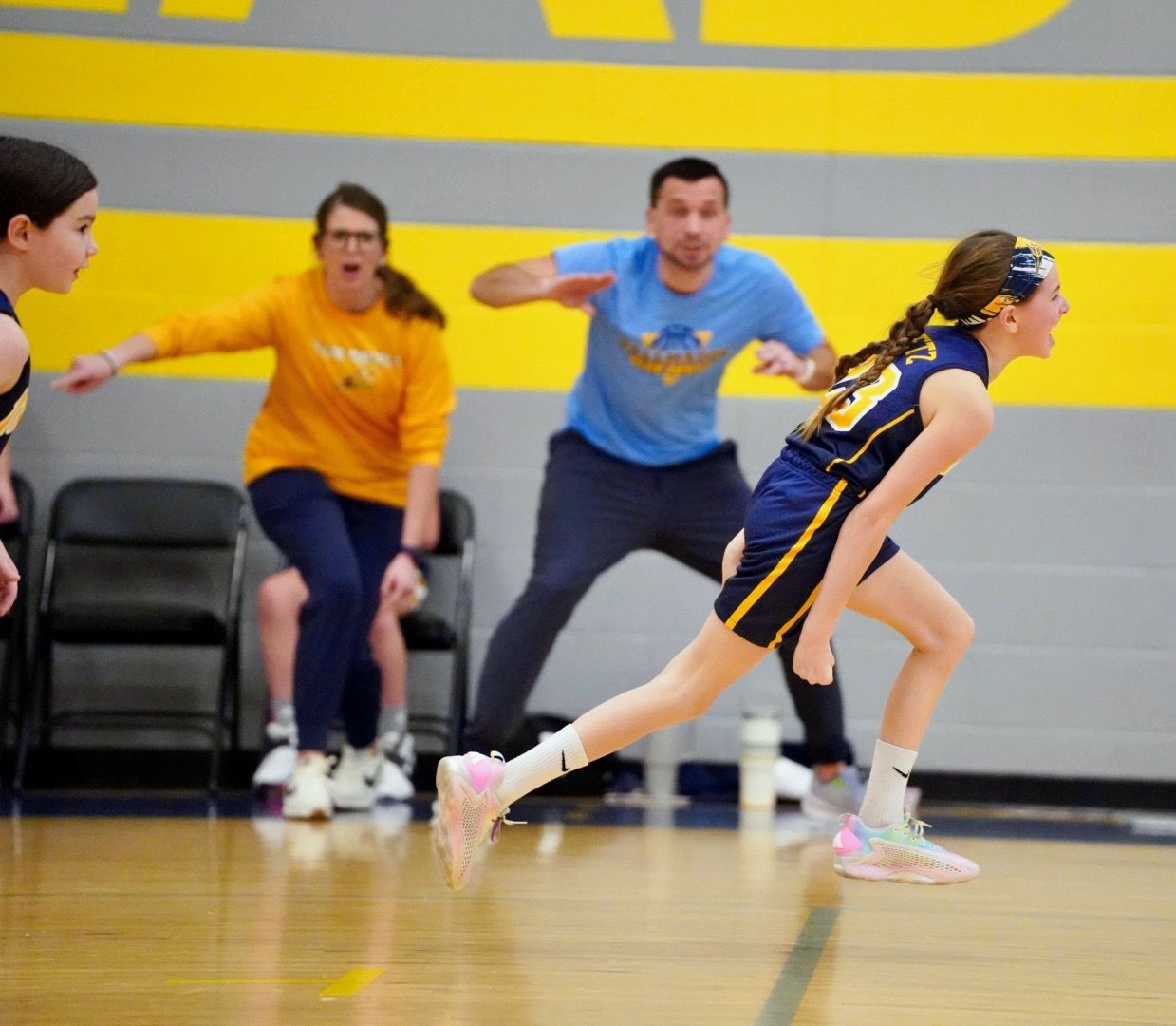 Players compete in an indoor volleyball game with one person diving to save the ball on a yellow-trimmed court.