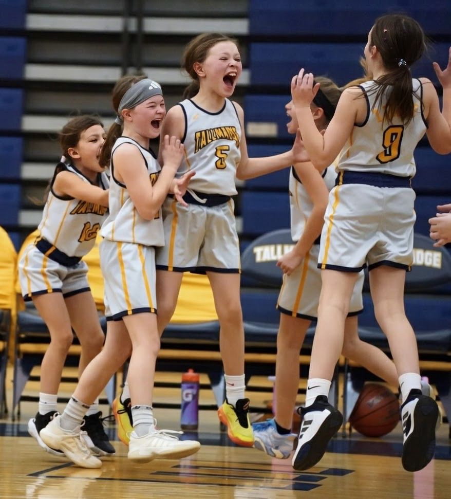 Basketball players celebrate and jump with excitement during an intense moment in their game on the court.