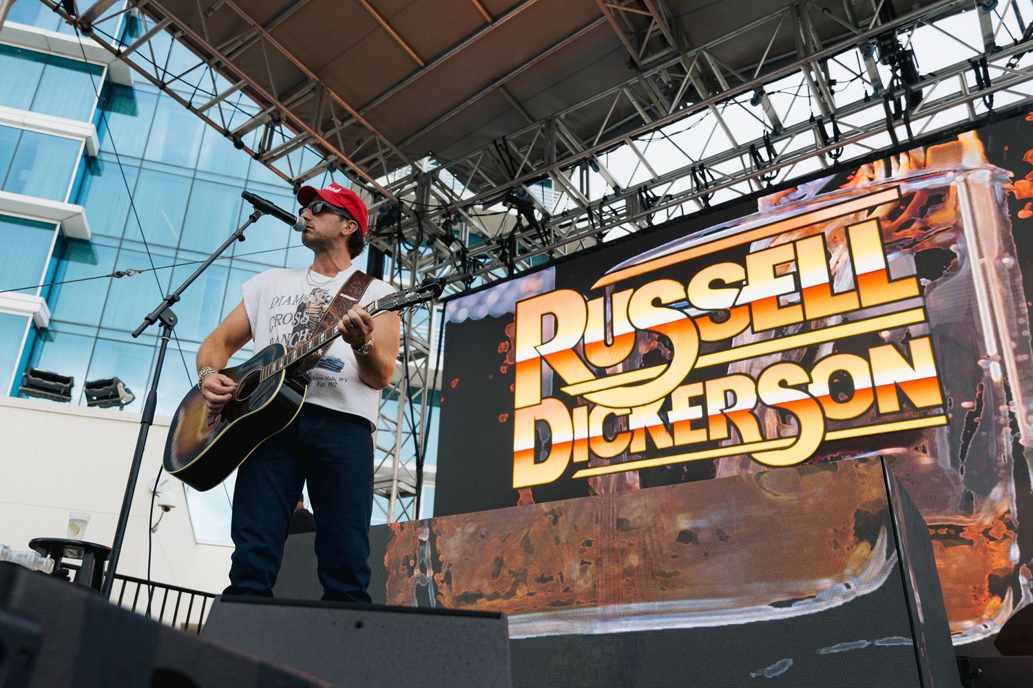 Russell Dickerson performing live on stage with acoustic guitar at an outdoor concert venue.