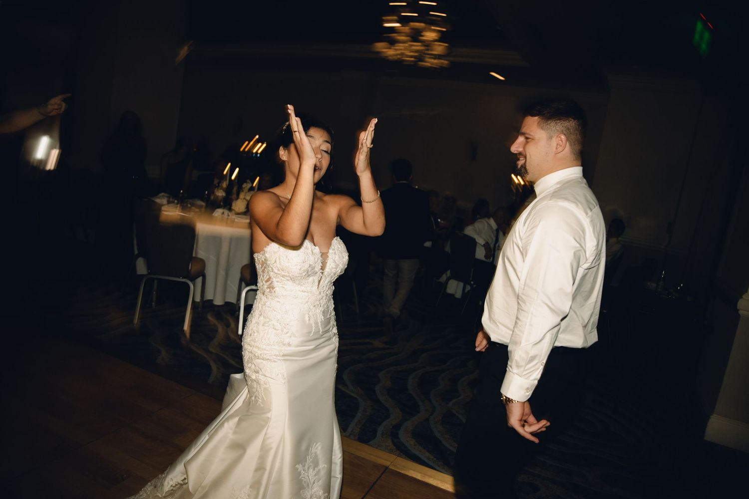 Bride and groom share a high-five moment on the wedding reception dance floor.