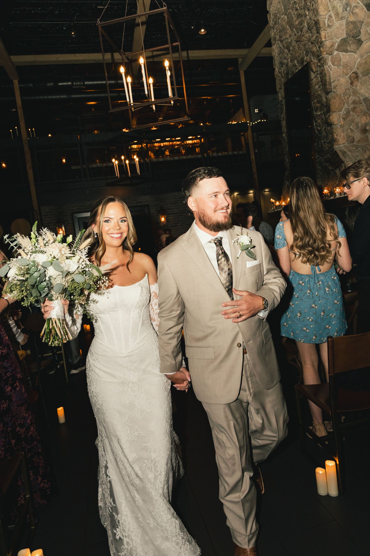 Bride and groom walking down the aisle after their wedding ceremony in a candlelit venue.