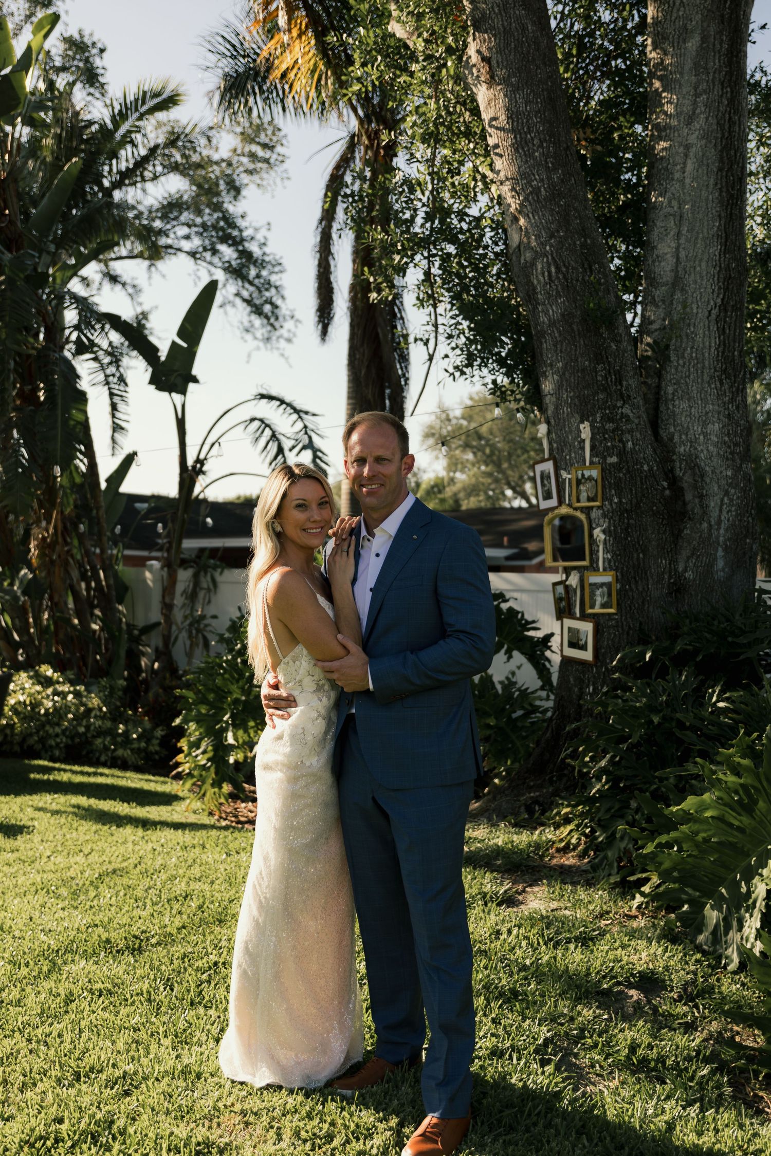 Bride and groom posing together in a lush tropical garden setting on their wedding day.