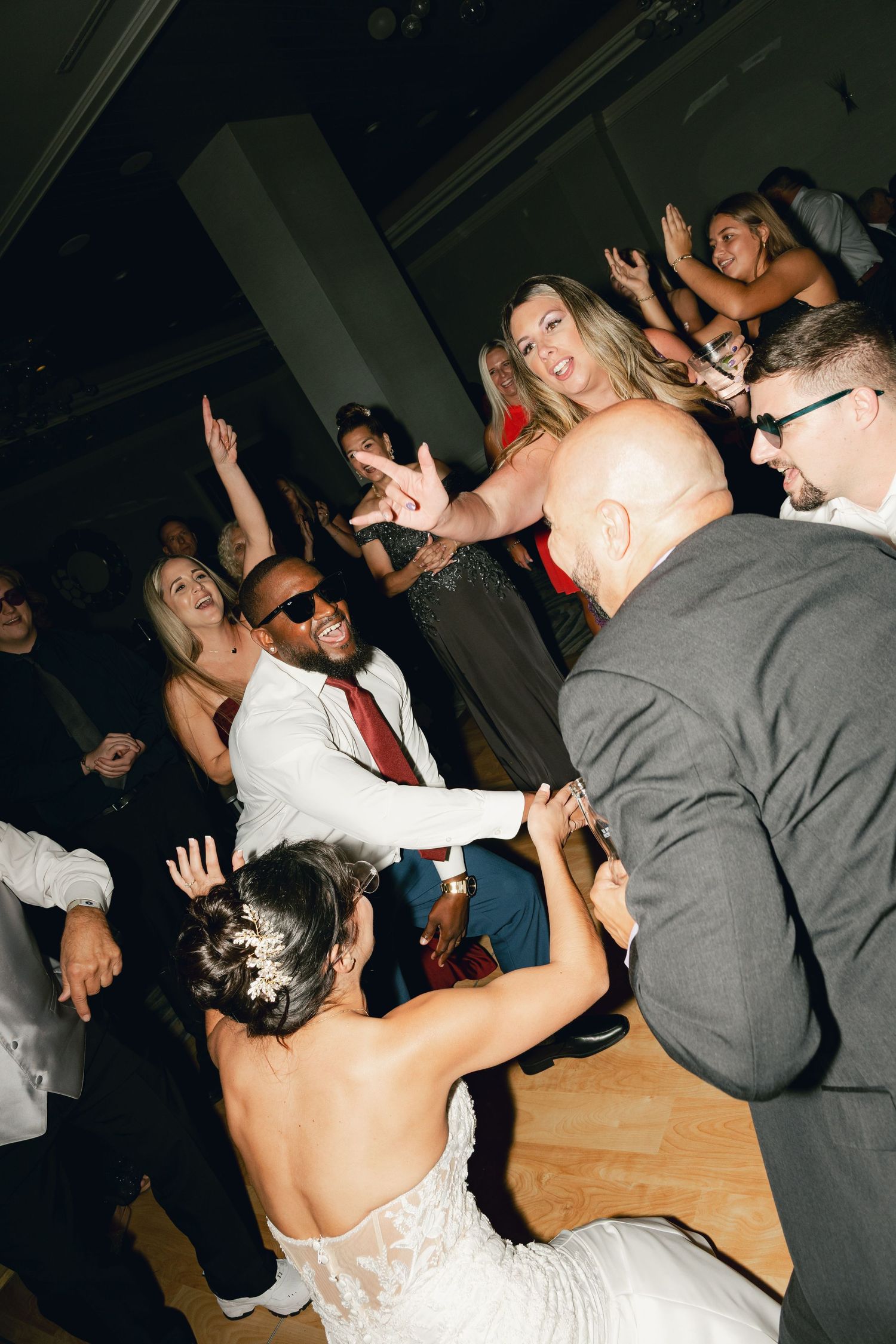 Lively wedding reception dance floor with bride, groom, and guests celebrating together.