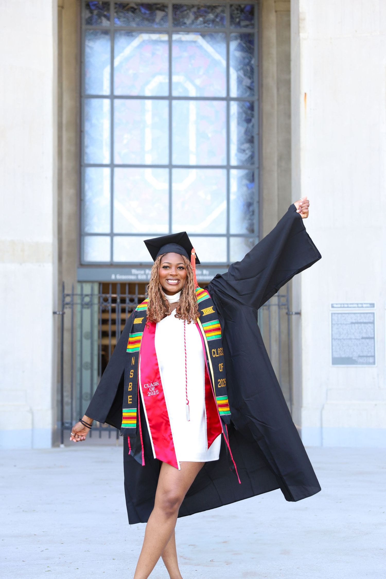Graduate in black gown and colorful stole celebrates with joyful poses during graduation photo session.