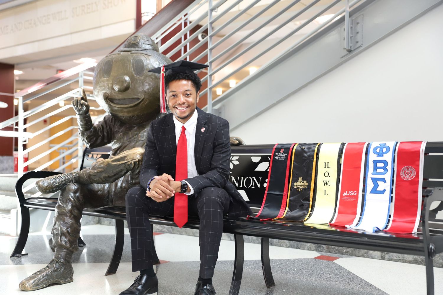 Person in business attire lies on an escalator handrail demonstrating playful behavior in an office building.