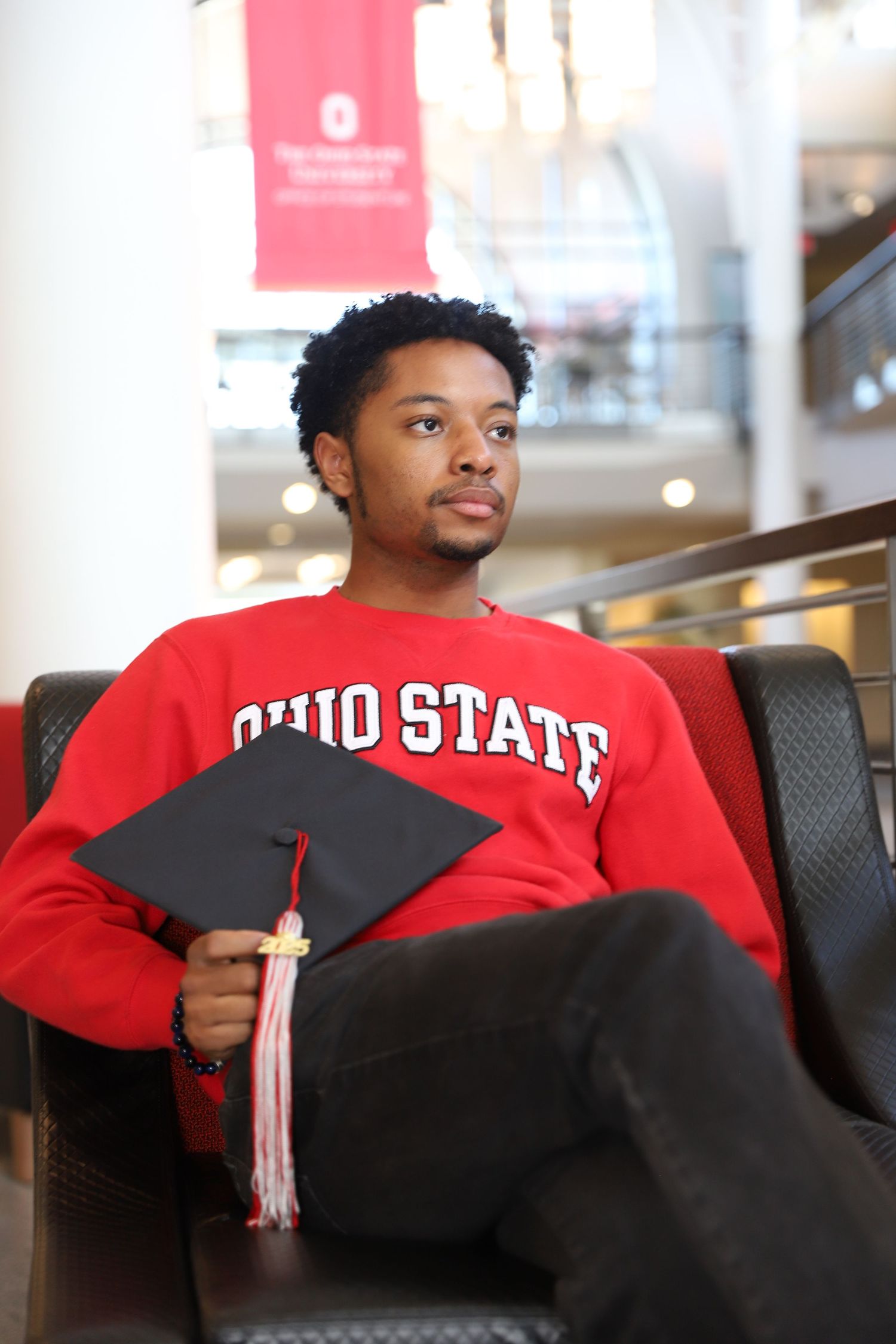 A student wearing an Ohio State sweatshirt sits casually in a chair.
