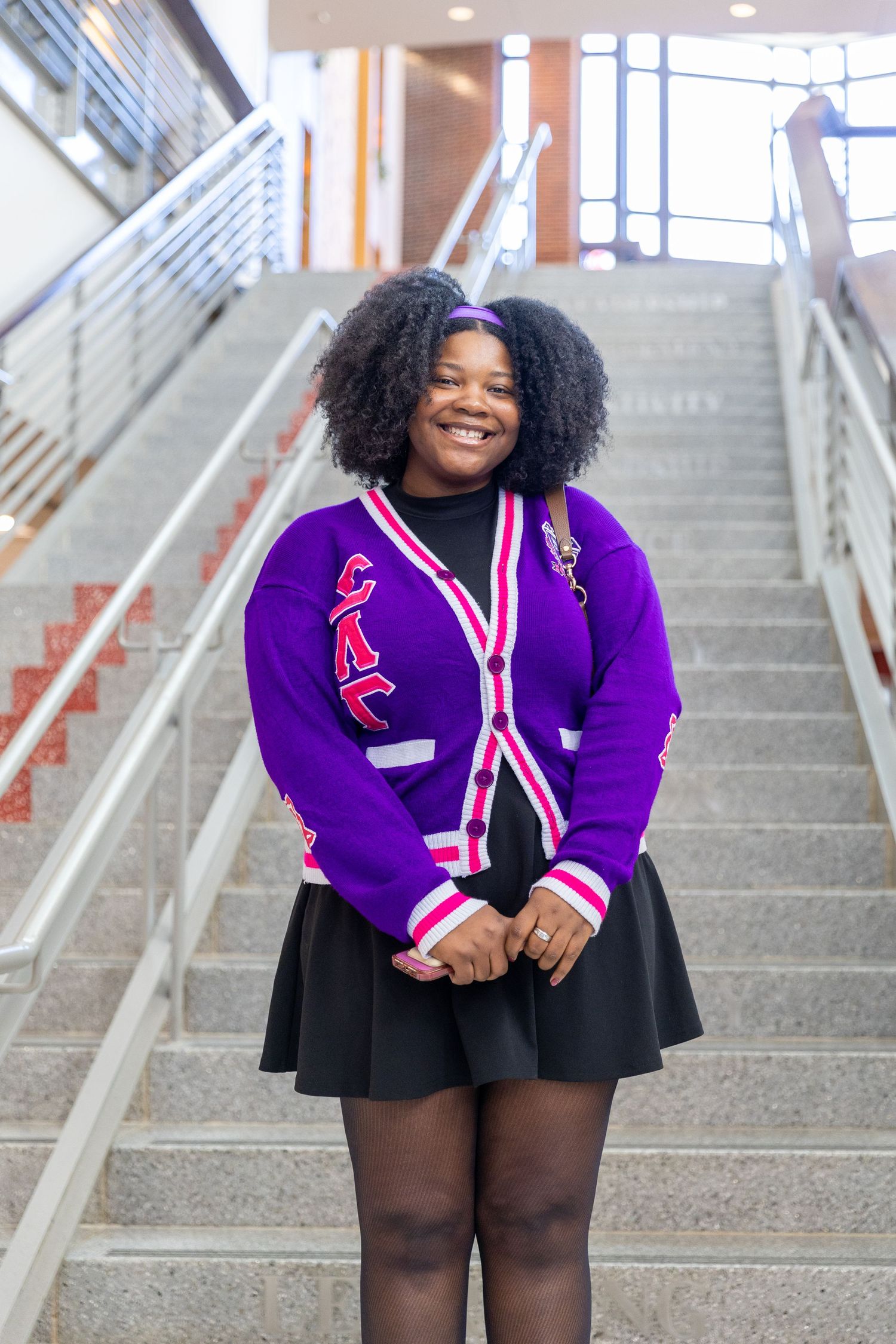 A person in a purple varsity jacket and black skirt poses on concrete stairs in a series of four photos.