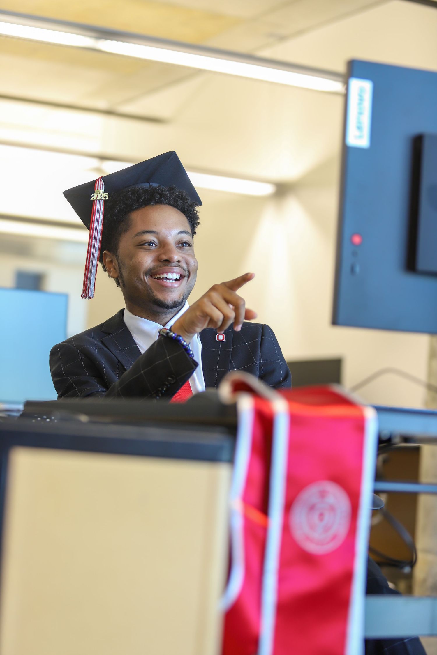 Students in graduation attire smile and celebrate during a commencement ceremony.