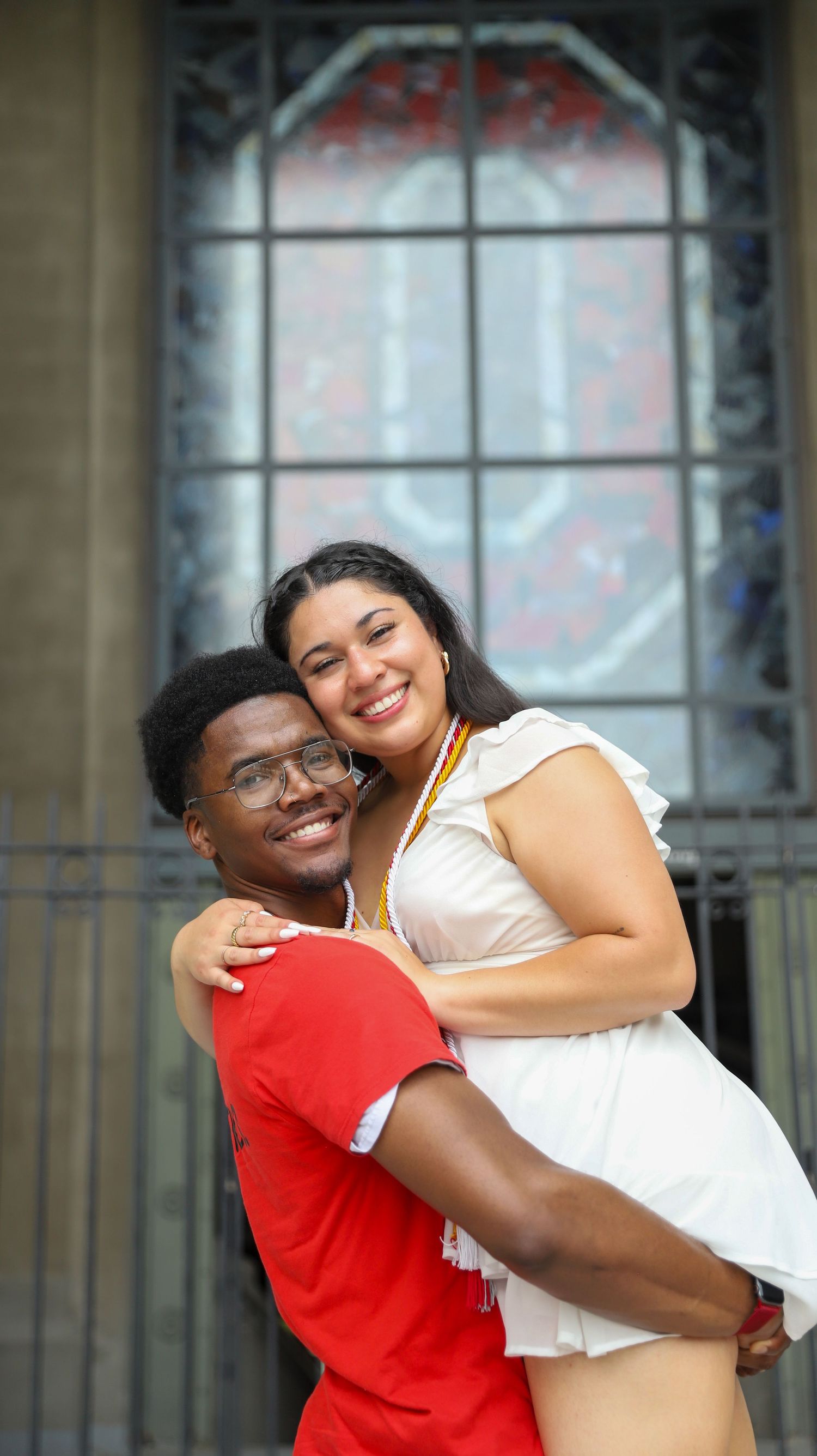 A joyful couple embraces and laughs together during an outdoor photo session near a stone building.