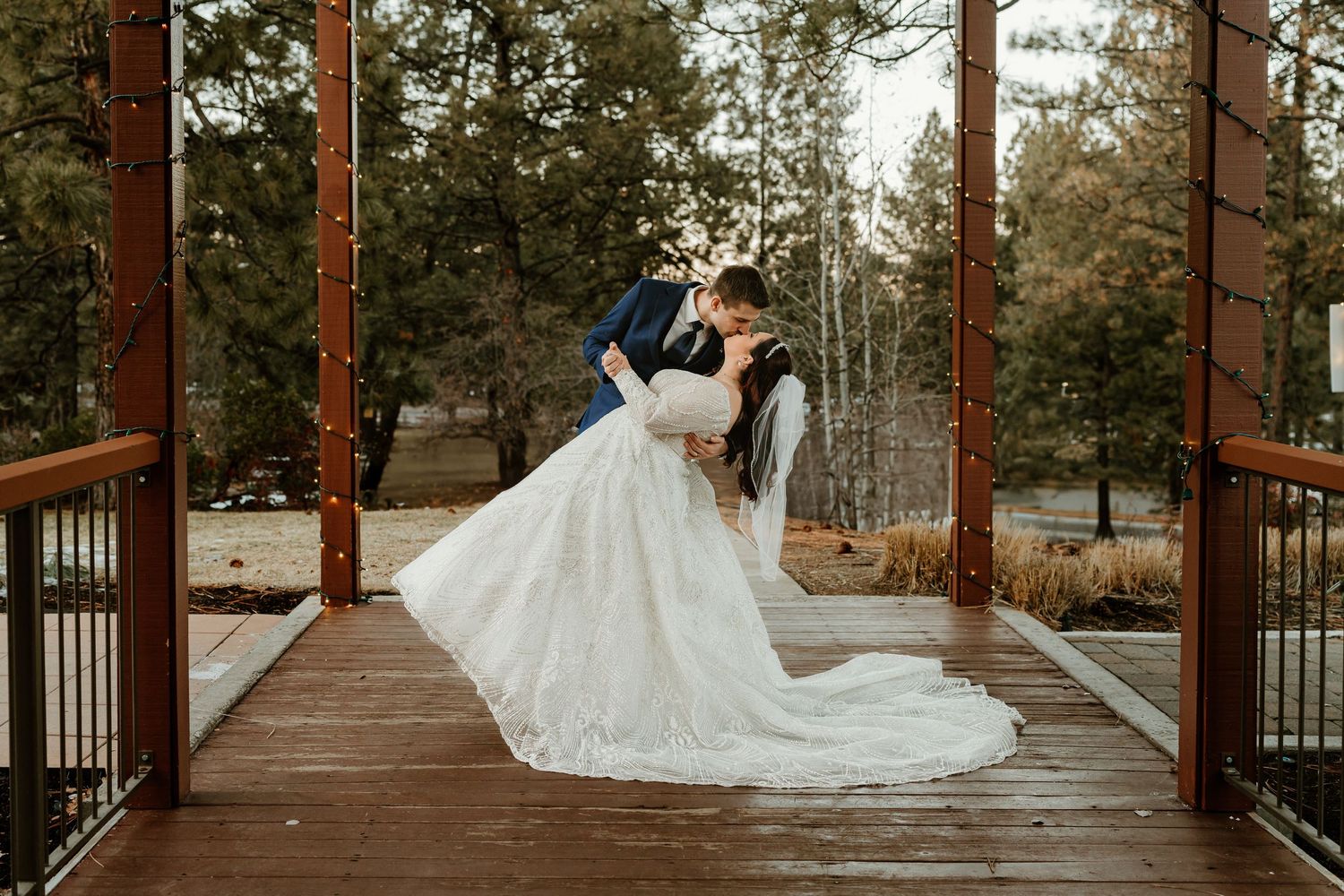 Bride and groom share a romantic dip kiss at a stunning outdoor wedding at Seventh Mountain Bend