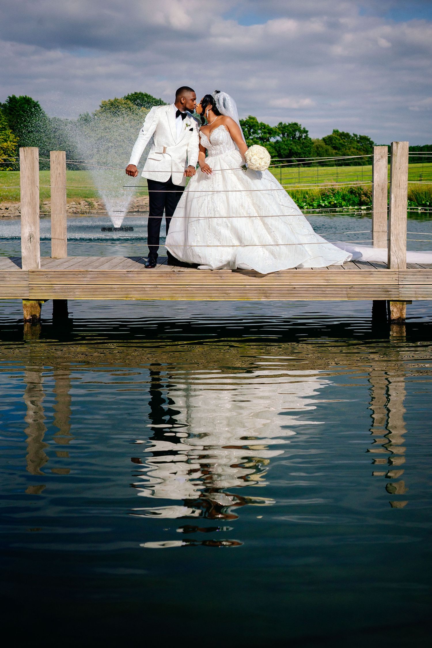 Romantic wedding photos on wooden dock with reflections in calm water below.