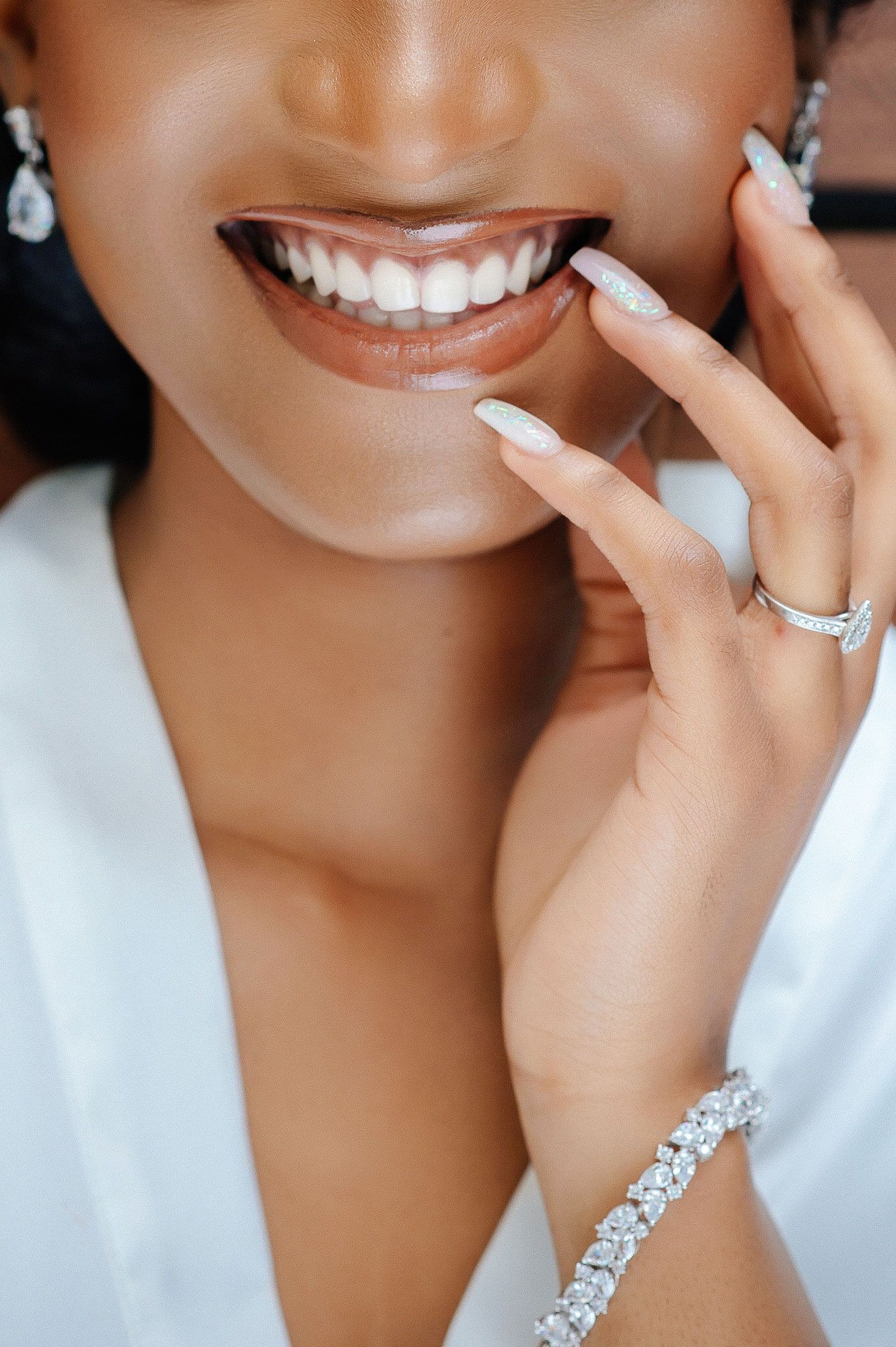 Close-up of a bright white smile and jewelry details showcasing elegant wedding day accessories.