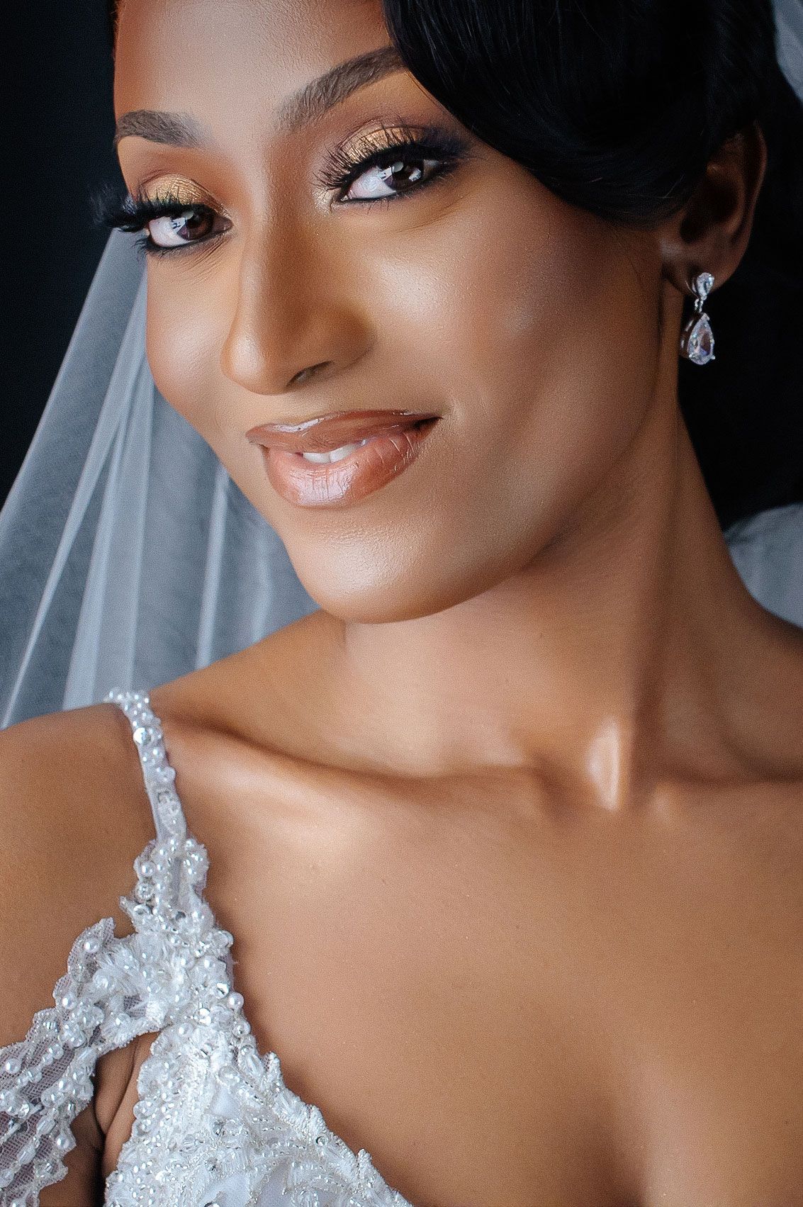 Close-up details of bridal jewelry and lace on an elegant wedding dress.