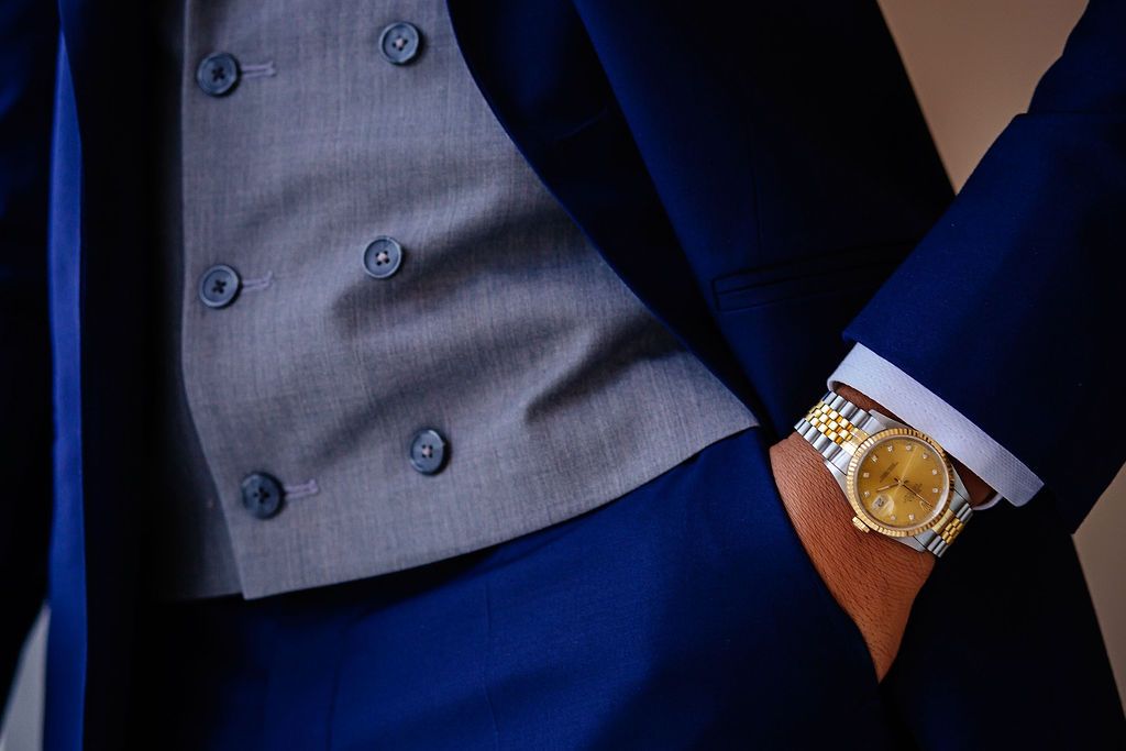A close-up view of a navy blue suit jacket sleeve with silver cufflinks and a white dress shirt underneath.