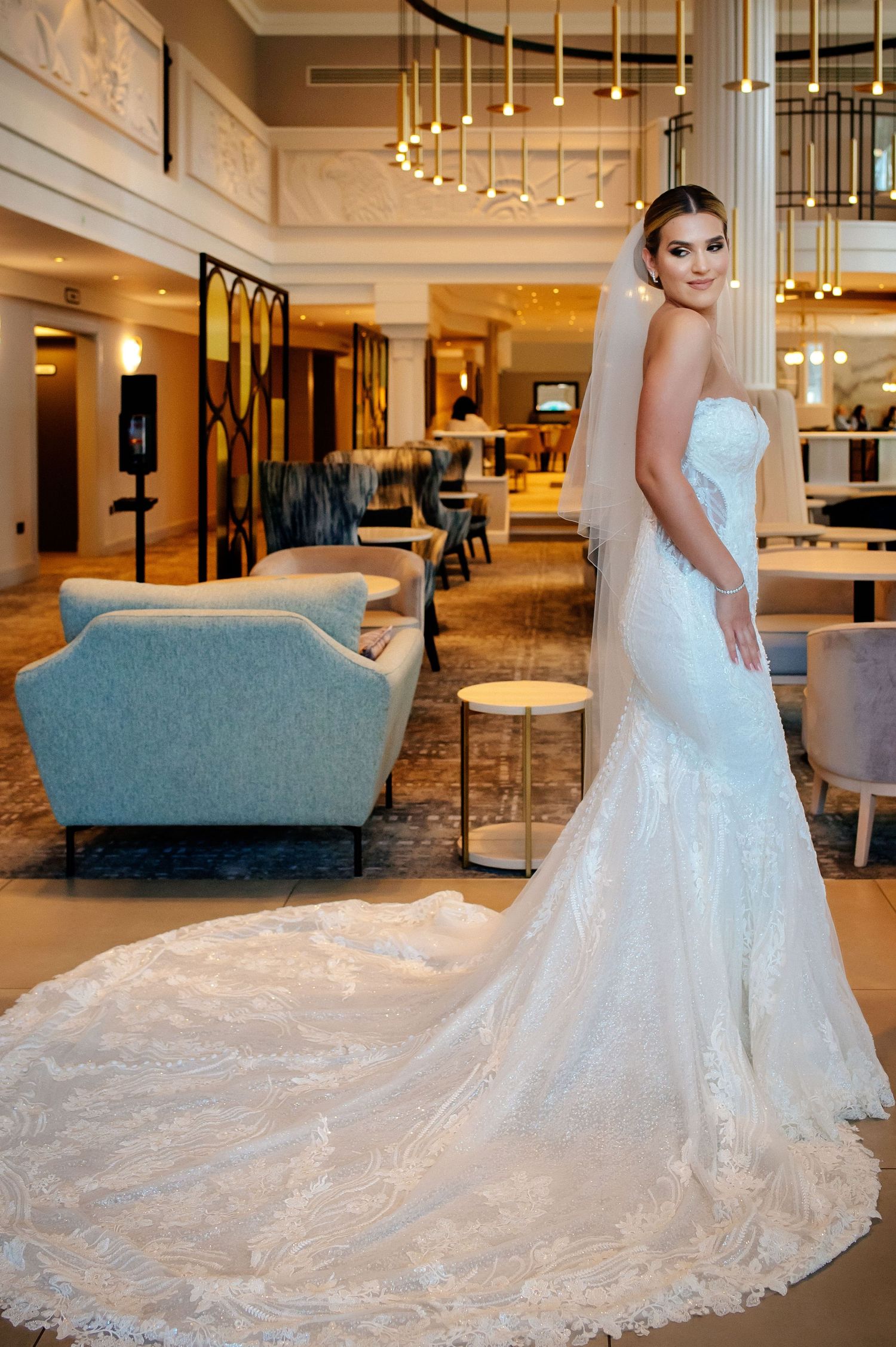 Elegant wedding dress with intricate lace details and long flowing train in a luxury hotel setting.