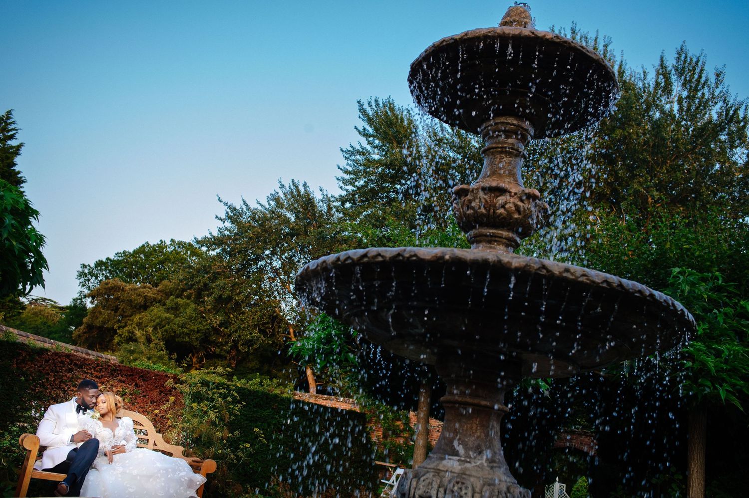 Ornate garden fountain with cascading water tiers in afternoon light.