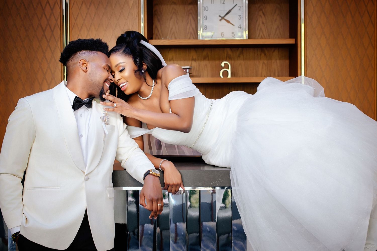 A bride and groom share a romantic moment during their wedding dance in a white and black formal attire.