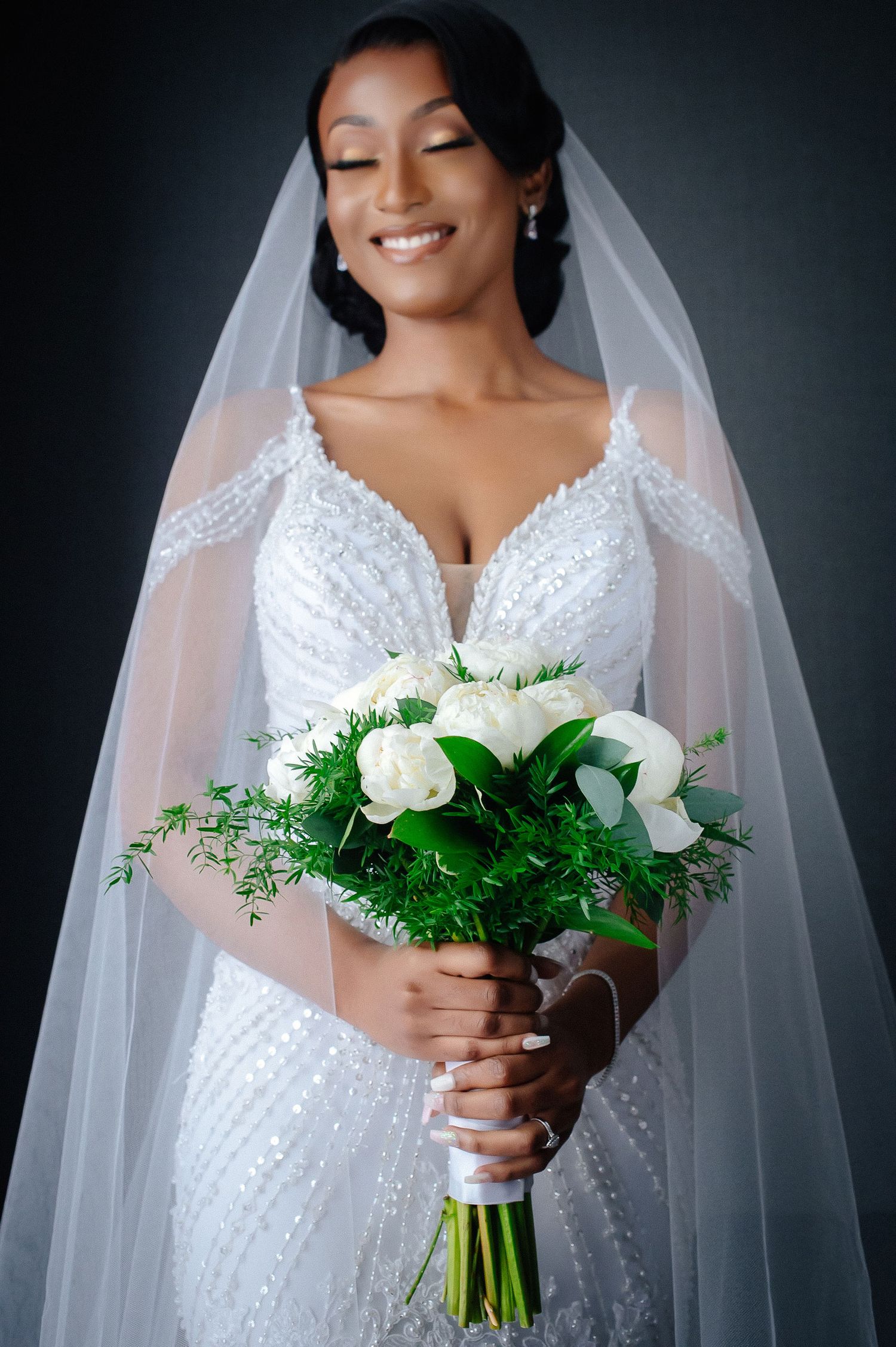 Elegant bridal portrait featuring a white bouquet and detailed lace wedding gown.