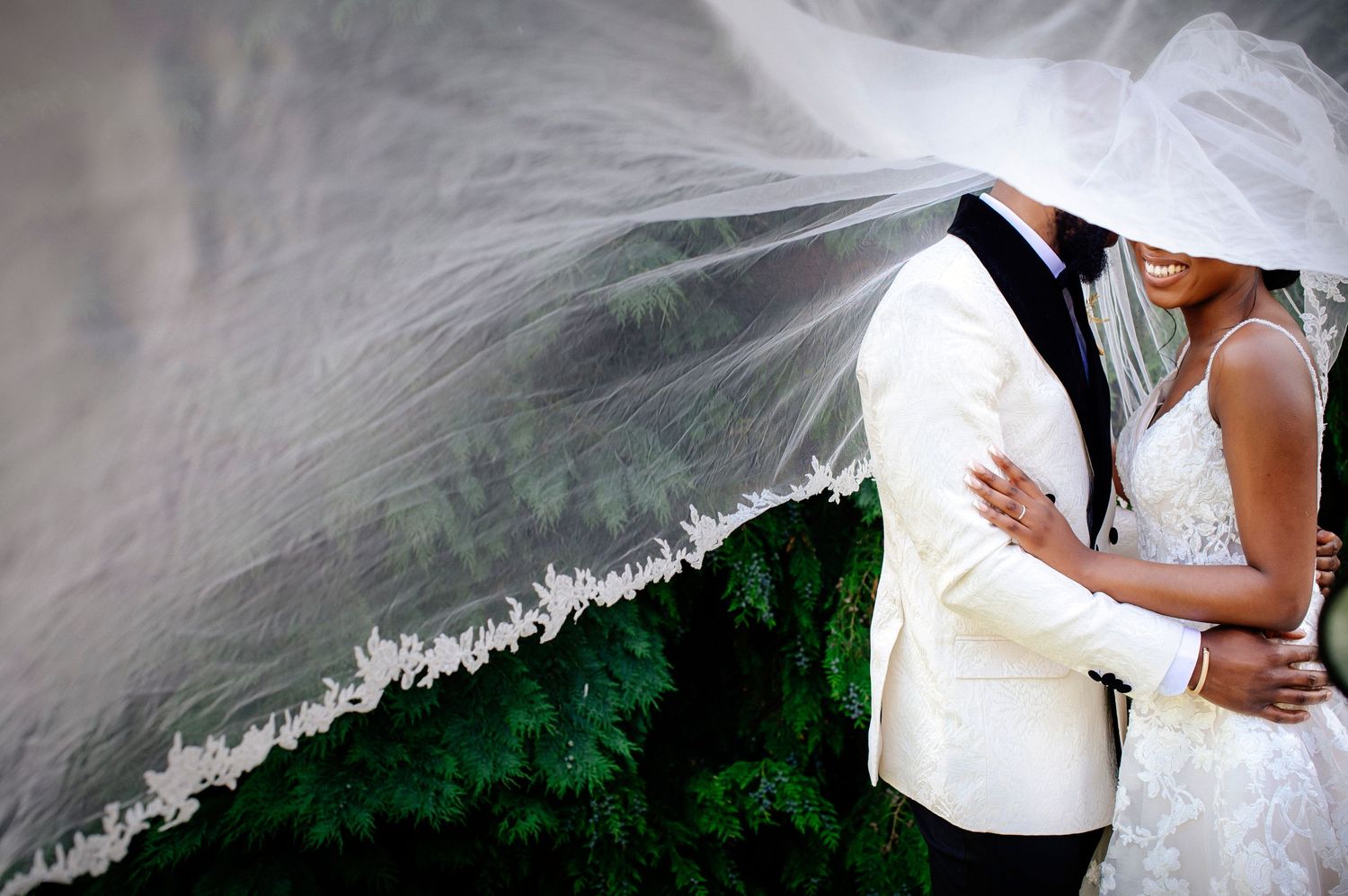 A flowing white wedding veil billows in the breeze against a dark background, creating an ethereal effect.