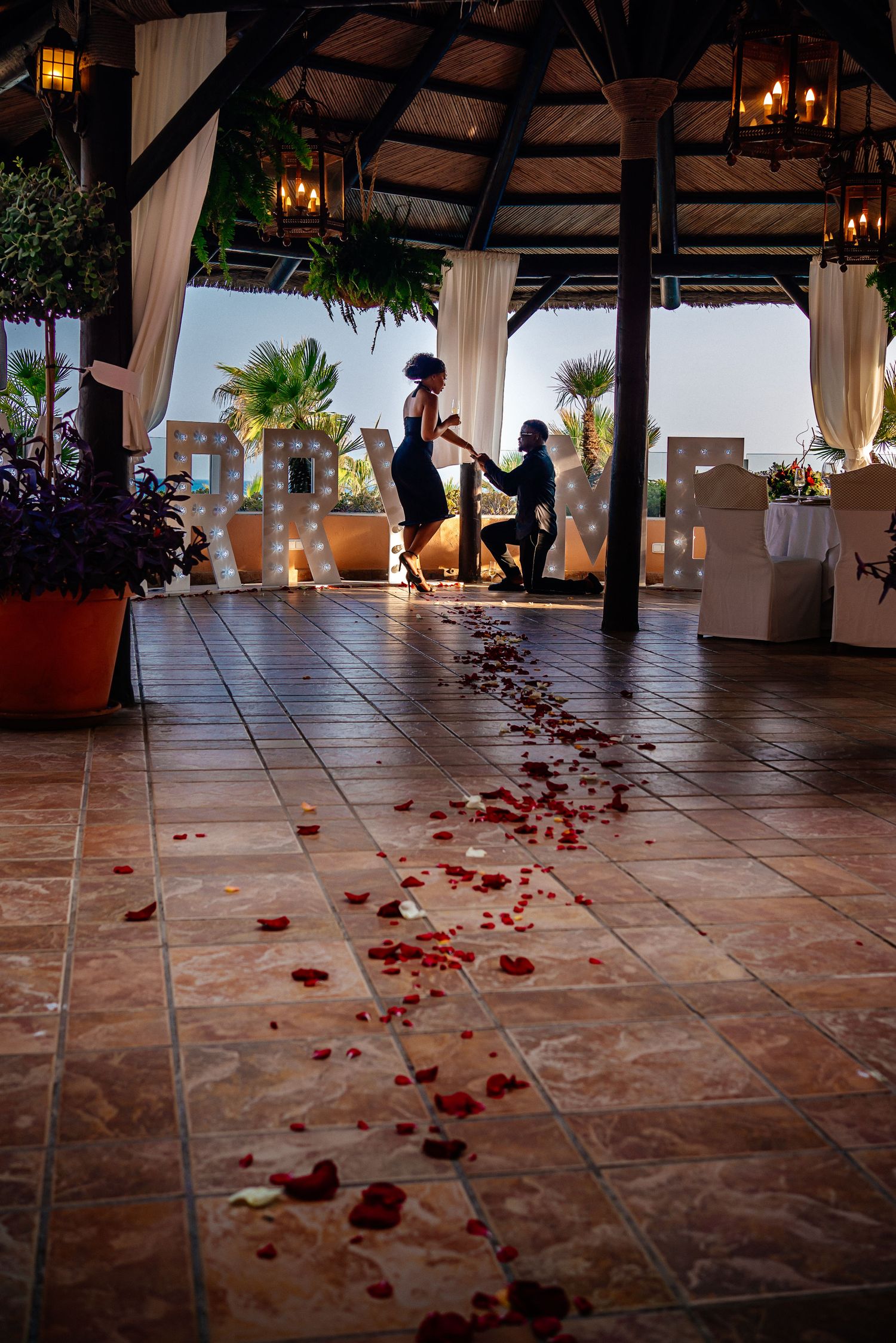 Rose petals scattered across terracotta tiles leading to an outdoor wedding venue.