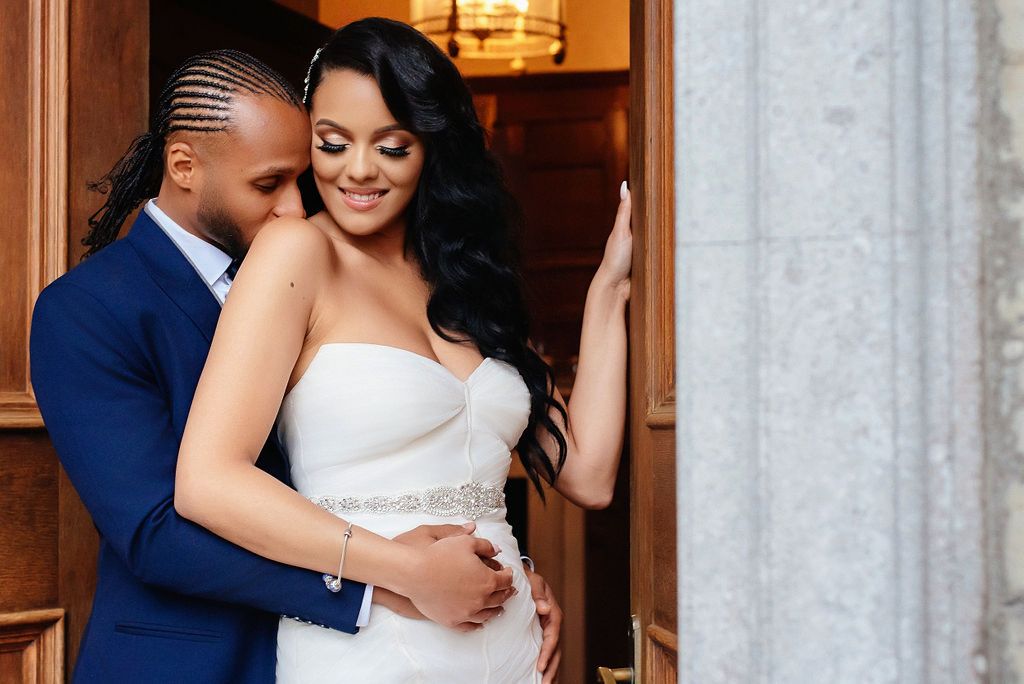 A couple shares a romantic moment in an elegant venue with warm lighting and wooden decor.