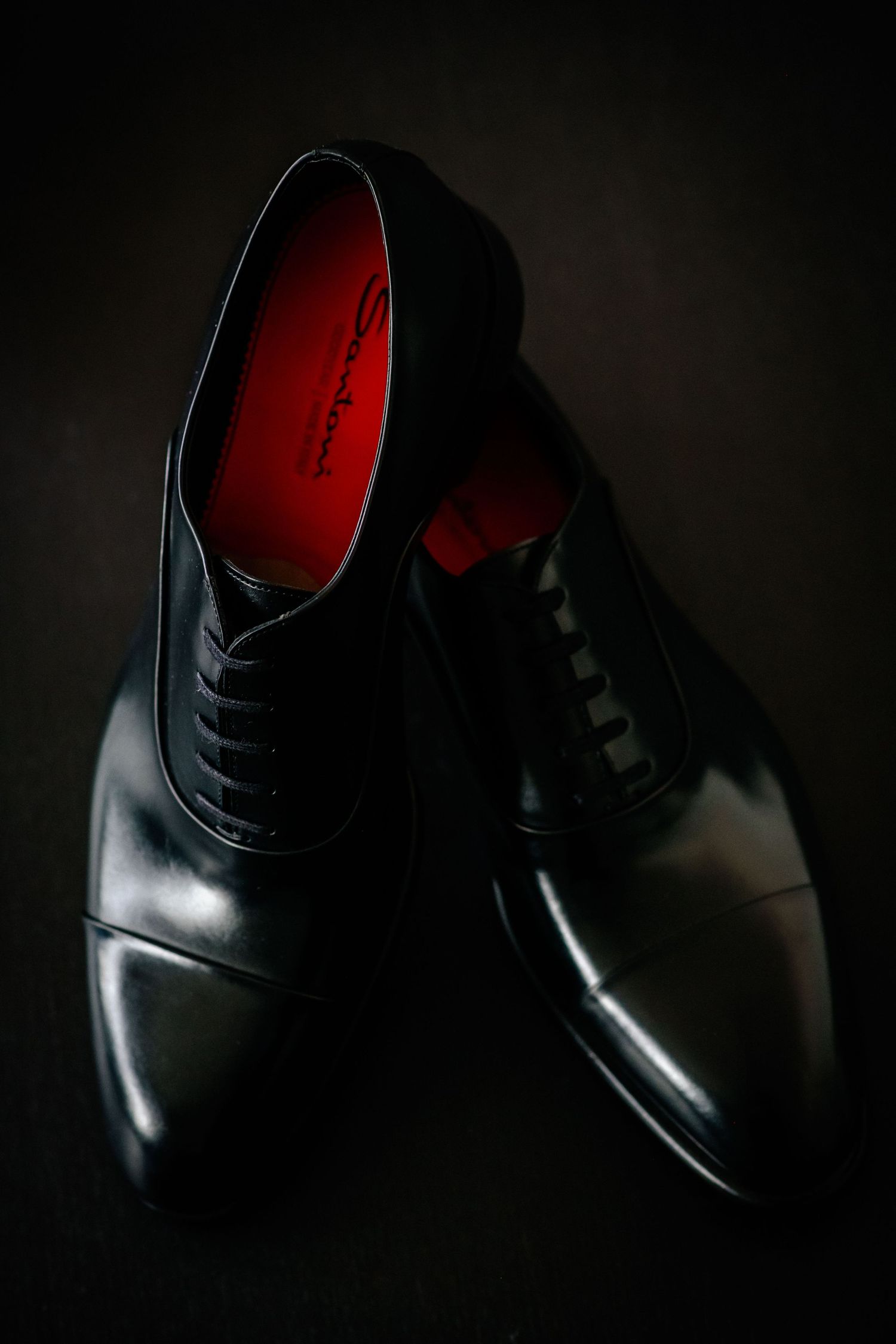 Elegant black leather dress shoes photographed dramatically against a dark background.