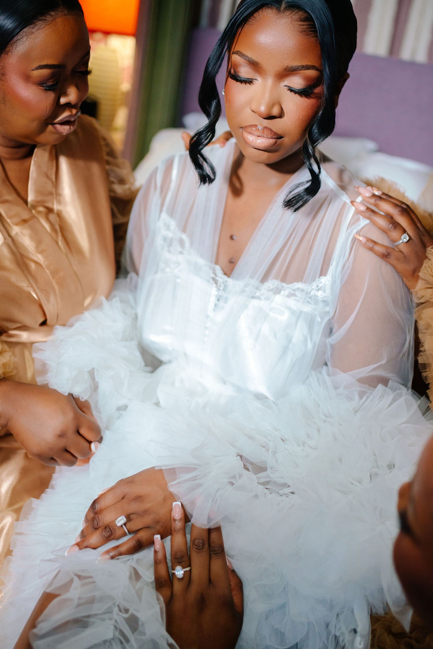Close-up of wedding dress details as bridal party helps with preparations.