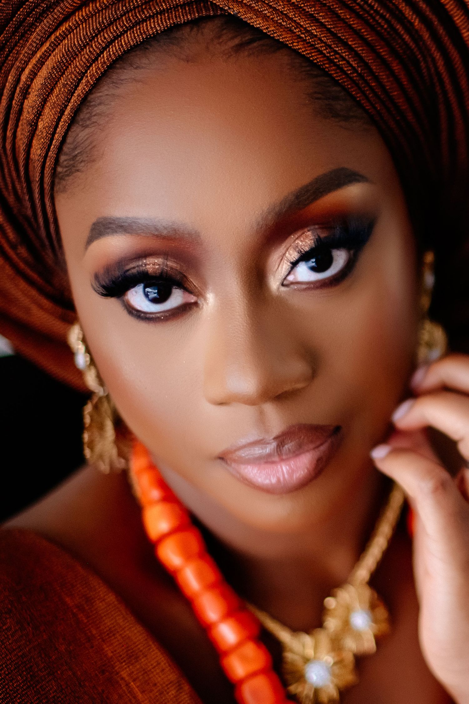 Close-up beauty portrait with orange coral beads and traditional headwrap.