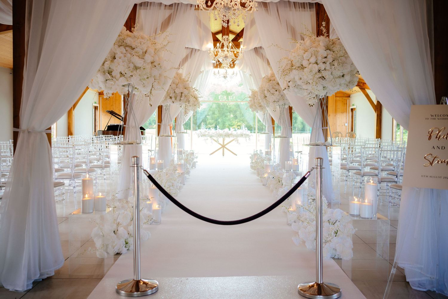Elegant white wedding venue interior with draped fabric and chandelier lighting.