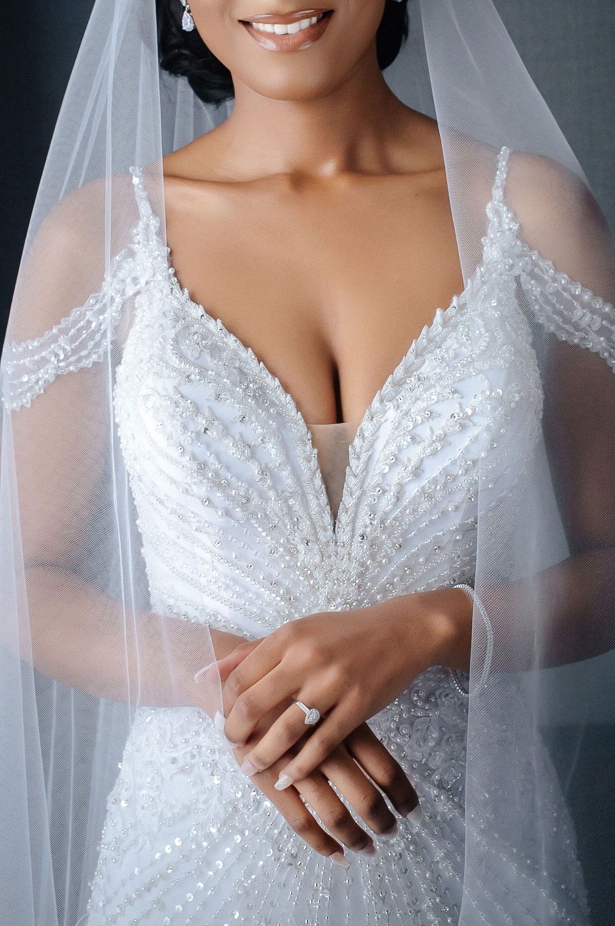 Detailed view of a beaded white wedding dress with delicate lace and veil.