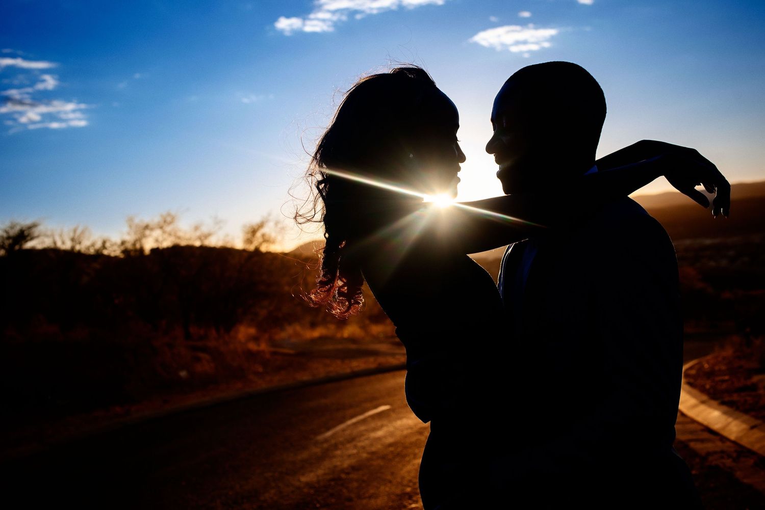 Silhouettes of a couple against a dramatic sunset backdrop creating romantic wedding portraits.