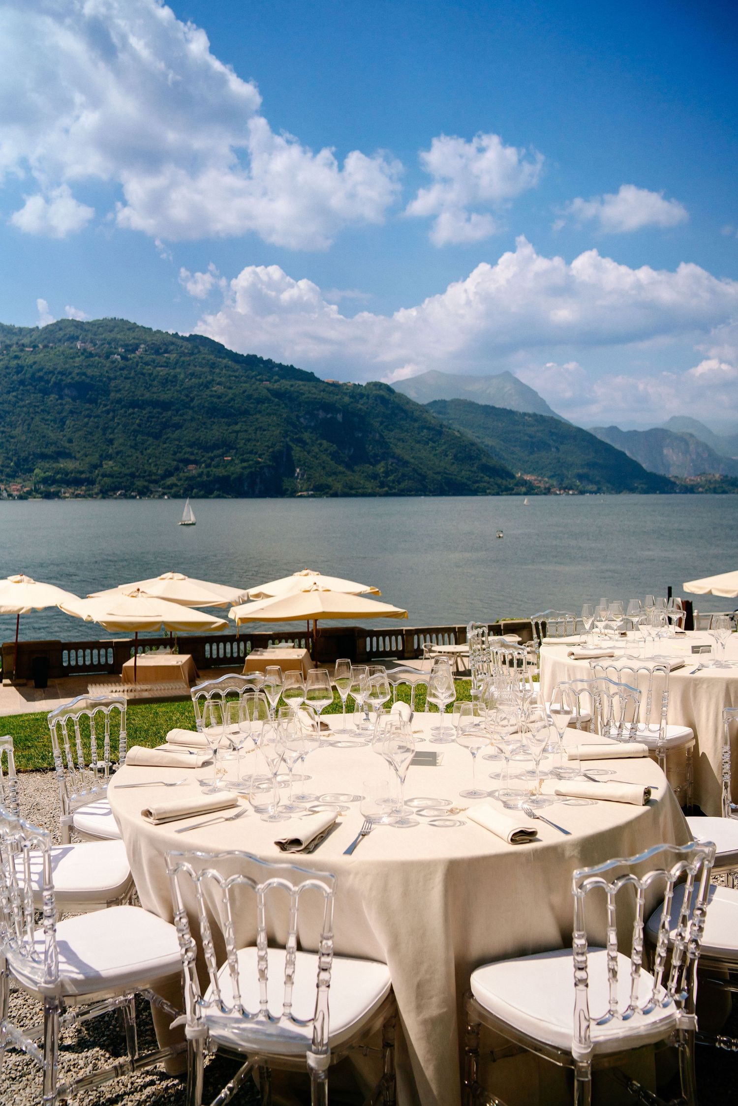Outdoor wedding reception setup with white tables and chairs overlooking a scenic mountain lake.