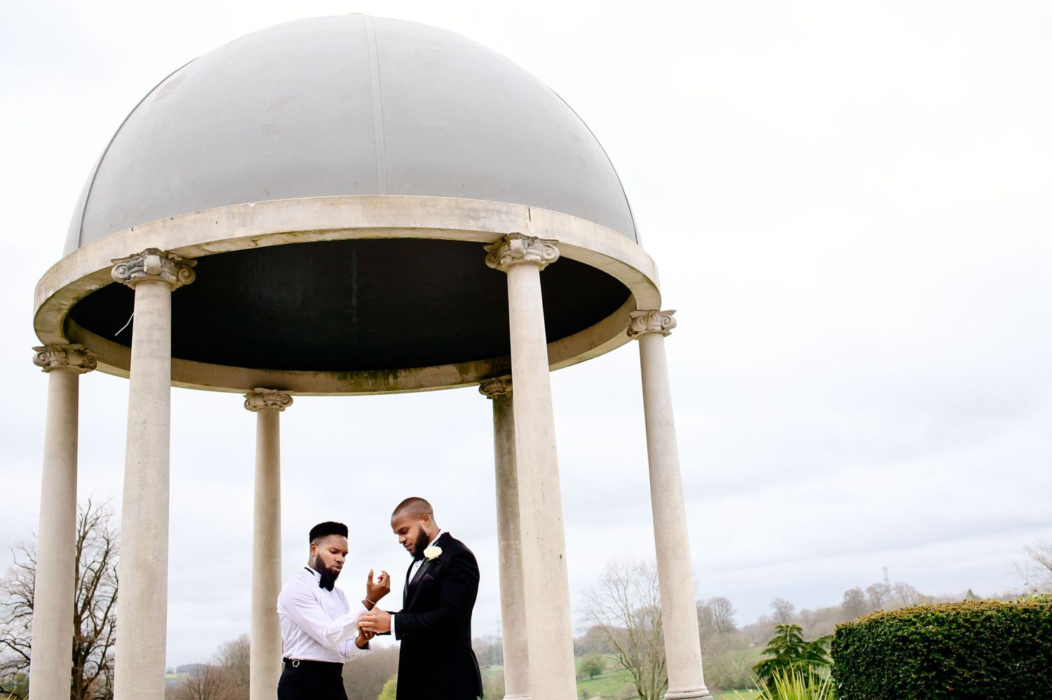 Two people standing under a classical domed gazebo structure.