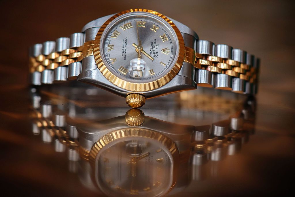 Close-up macro shots of a luxury gold and silver Rolex watch from multiple angles showing intricate bracelet details.