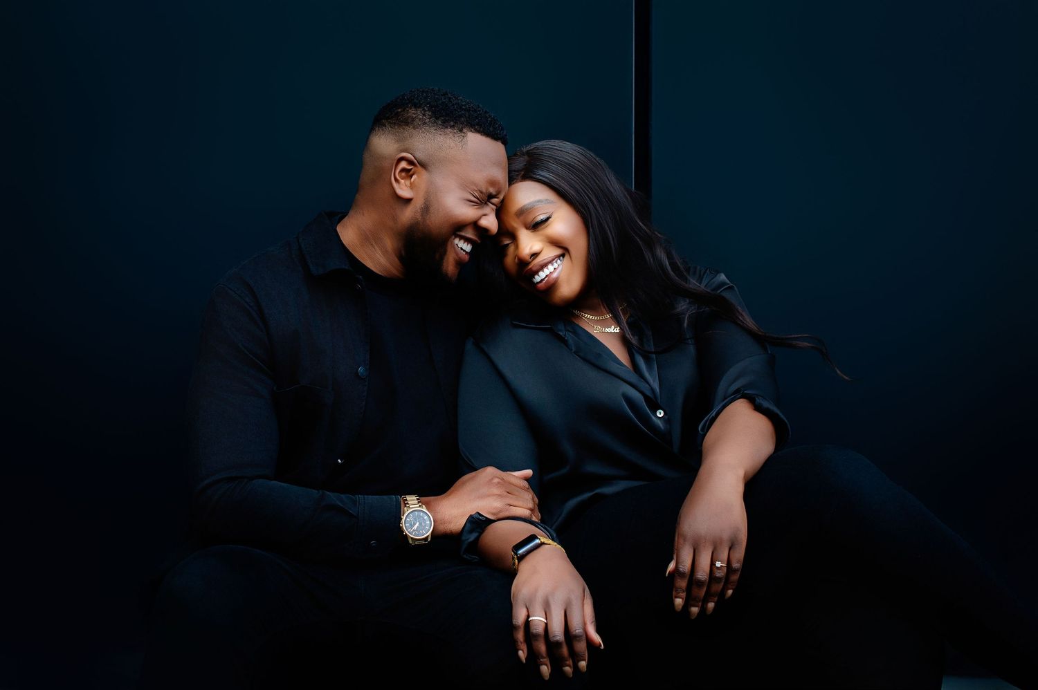 A couple shares an intimate moment together against a dark background in a romantic portrait session.