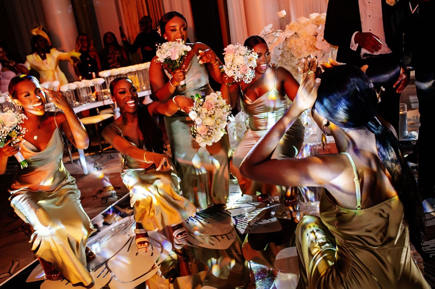 Wedding reception dance floor filled with guests celebrating under warm lighting.