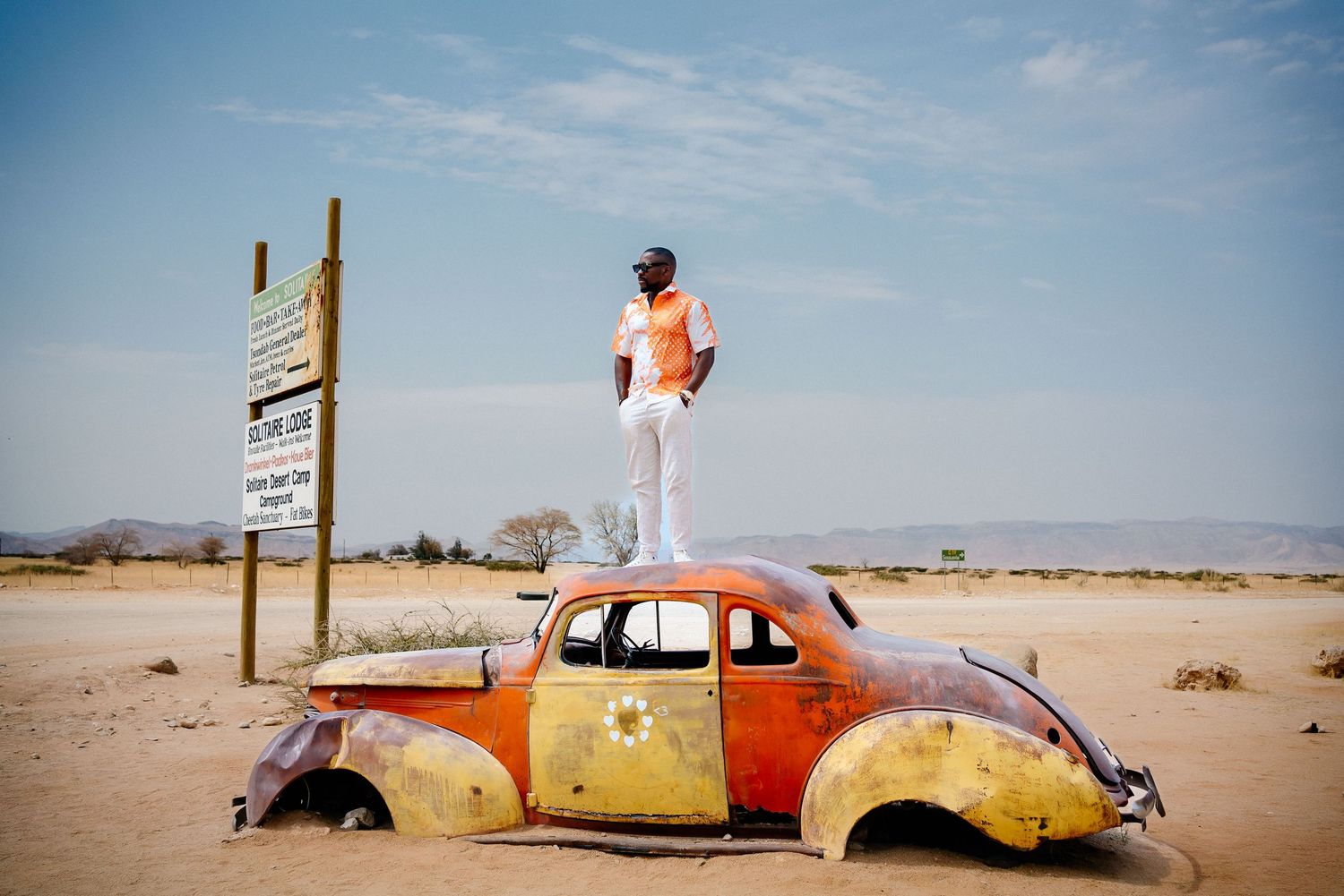 Vintage orange Volkswagen Beetle abandoned in a vast desert landscape.