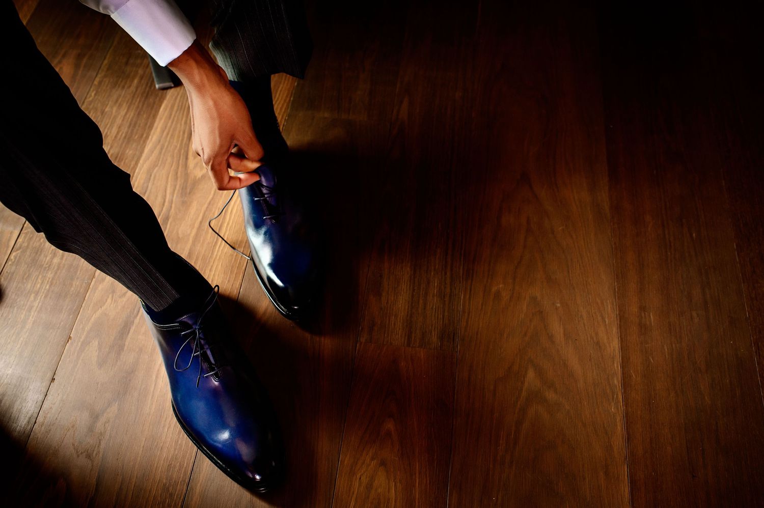 Detail shots of formal shoes and suits against dark wooden flooring.