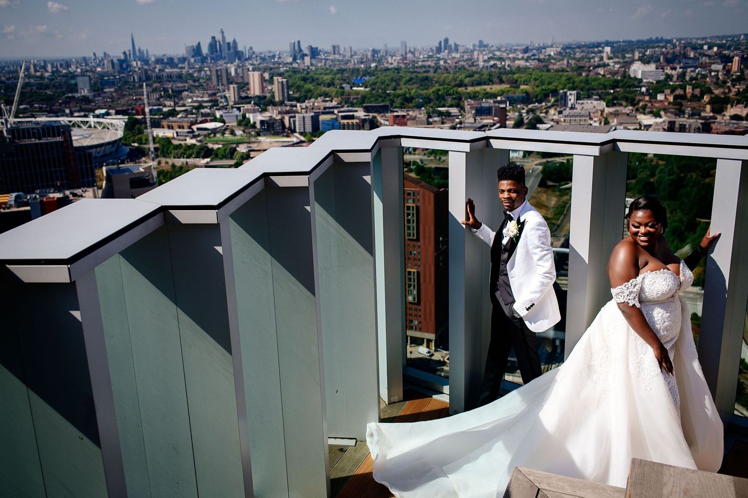 Panoramic cityscape view with wedding party on rooftop.